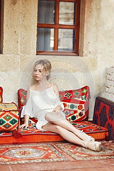 Morning girl resting sitting on a Turkish sofa. A woman in light clothes is preparing for the arrival of her beloved man