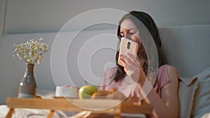 Morning girl using smartphone at home closeup. Smiling serene woman dreaming