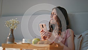 Morning girl using smartphone at home closeup. Smiling serene woman dreaming