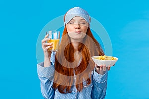Morning, healthy lifestyle and people concept. Feminine good-looking redhead woman in sleep mask and pyjama, close eyes