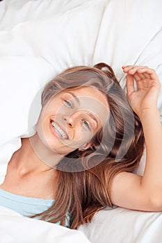 Morning at Home. Woman lying on bed laughing playful top view close-up