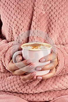 Morning hot chocolate on a cold autumn morning, hands holding a mug with a drink, cozy atmosphere, vertical