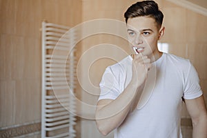 Morning hygiene, the boy brushes his teeth near the mirror