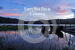 Morning inspiraitonal quote - Every New Day is A Blessing. With blue sunrise over lake with wooden fishing boats at sunrise. photo