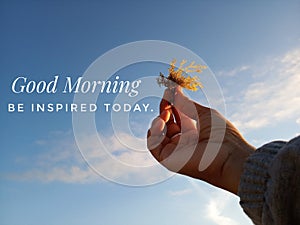 Morning inspirational quote- Good morning. Be inspired today. With blurry image of  young woman hands holding sea weed against the