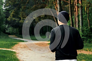 Morning jog in the park, a man in a black sports suit running around the park copy space