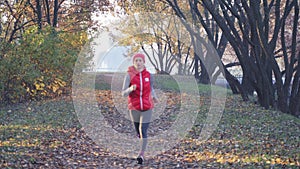 Morning jogging of a young woman in a city park in a dense fog. Healthy lifestyle in any weather concept