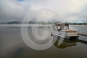 Morning landscape with autumn fog over the lake, a wooden pier and boats on the lake Massavippi, fog and sunlight.