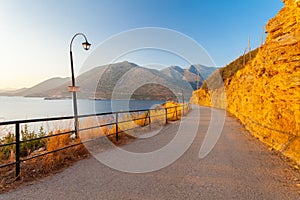 Morning landscape with lamps near the road, mountains and sea.