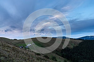 Morning landscape in the mountains. Dawn in the mountains. Rural huts on top of the mountain. Cloudy sky over the village