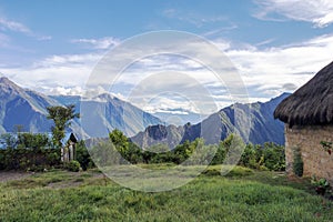 Morning landscape with Peruvian Andes mountains peaks and straw roofed small house at sunrise photo