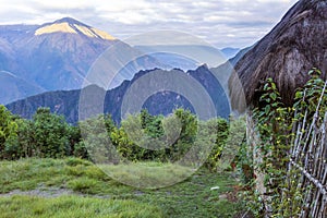 Morning landscape with Peruvian Andes mountains peaks and straw roofed small house at sunrise photo