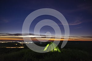 Morning landscape, tent against the backdrop of the sunset and city lights on a hill in Ukraine