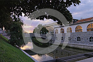 Morning landscape view of Ljubljana. Embankment of Ljubljanica River with illuminated colorful historic houses