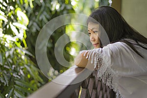 Morning lifestyle portrait of young happy and beautiful Asian Korean woman enjoying the view from hotel room terrace or home