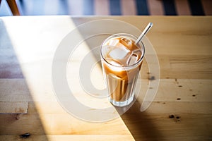 morning light casting shadow on iced chai latte on caf table