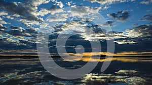 Morning light reflection in lake Malaren in Sweden, Sky reflected in calm water dramatic clouds, Golden horizon