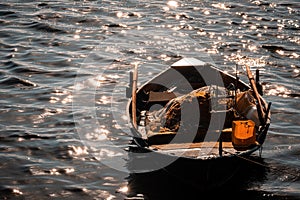 Morning light with almost sunlight, orange radius spread across sea, with fishing boat and sparkling sea surface. Small fishing