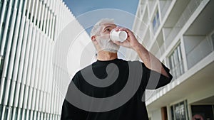 Morning man drinking coffee at downtown closeup. Senior male reading newspaper