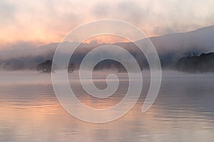 Morning mist drifting over a lake at sunrise