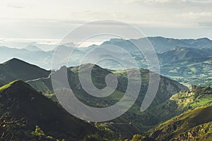 Morning mist in the mountain peaks on natural landscape. Green valley on background foggy dramatic sky. Panorama horizon