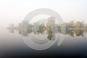 Morning mist over the lake with reflection in the water. Fog on a river
