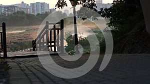 Morning mist over the river. Taken at dawn. High-rise city buildings are on the horizon. The camera moves on the slider to the