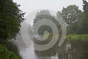 Morning mists slowly reveal the slowly flowing river