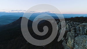 Morning mountain landscape with waves of fog. Shot. Top view of mountains in fog and rock at dusk. Mystic foggy