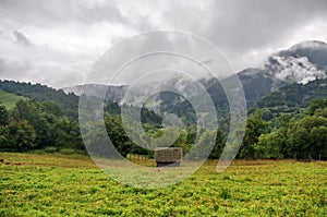 Ráno Příroda, krajina panoramatický výhled s mlžnými horami, lesem, zelenou loukou a starým srubem přímo v krásné přírodě.