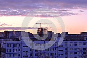 Morning city panorama with a view of residential apartment buildings, a tower crane and a high-rise building under construction