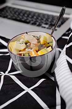Morning in pastels: fruit breakfast and laptop on a black bed