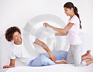 Morning playfulness. A fun-loving young couple having a pillow fight on their bed.