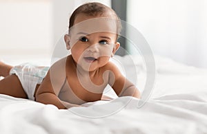 Cute adorable little African American kid lying on bed