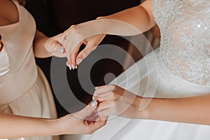 Morning preparation of the bride. Close-up of a bridesmaid's hands fastening the many buttons on the bride's wedding dress