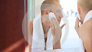 Morning regular bathroom scene: young adult man foames his face before shaving