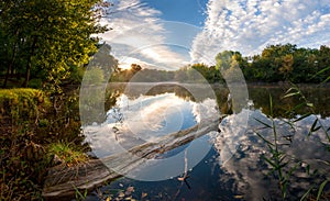 Morning on river with majestic clouds reflection in water