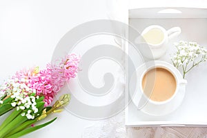 Morning romance breakfast, cup of coffee, milk jug and cake with decor of pink hyacinth. Spring concept.