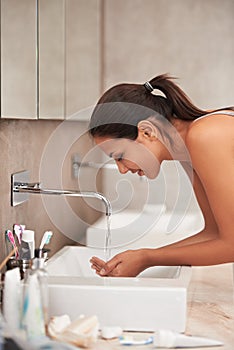 Morning routine. A beautiful young woman washing her face in her bathroom.