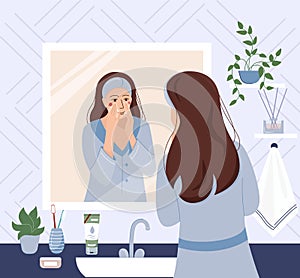 Morning routing. Young woman standing in front of mirror and cleansing or moisturizing her skin. Everyday personal care, skincare