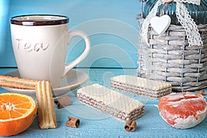 Morning scene with cup of tea or coffee, Dutch cookie stroopwafel, Delfts blue souvenir, on blue table
