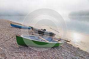morning scenery at lake Sylvensteinsee, gravel beach with rowing boats. foggy sky with copy space