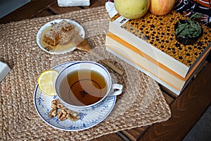 Morning setup at balcony, books to read, cup of natural tea, teapot, organic honey, fresh green tea leaves and organic fruits