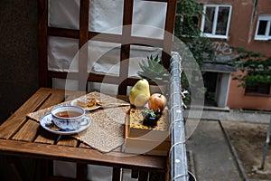 Morning setup at balcony, books to read, cup of natural tea, teapot, organic honey, fresh green tea leaves and organic fruits
