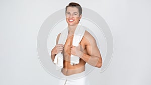 Young man standing with towel at white studio