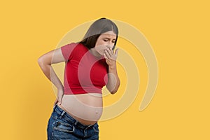 Morning Sickness. Pregnant Woman Suffering Nausea While Standing Over Yellow Studio Background