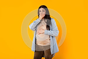 Morning sickness. Young pregnant woman suffering nausea, covering mouth with hand and touching belly, feeling unwell