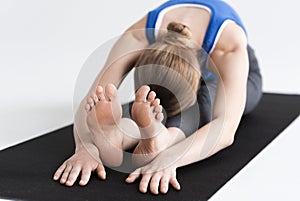 Morning sports practice. Young woman doing stretching or yoga on mat, white background