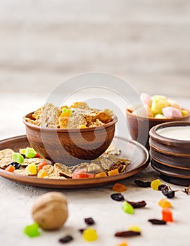 Morning still life. Healthy breakfast wheat flakes, walnuts, candied fruits, raisins, milk on a gray textured background