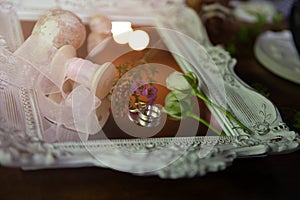 Morning sun rays fall on wedding rings beautifully laid out among the wedding accessories